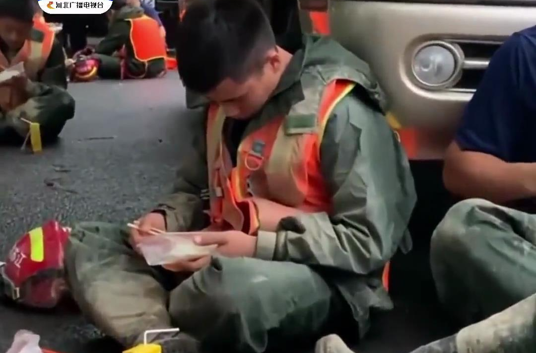【参加救援的人民子弟兵靠在车旁累到睡着，手里还捧着没吃完的盒饭】